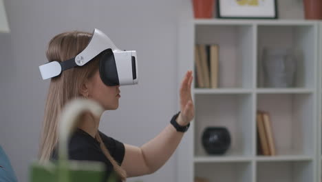 interactive-educational-program-with-using-HMD-display-woman-is-wearing-VR-headset-in-home-gesticulating-by-hands-portrait-of-female-user